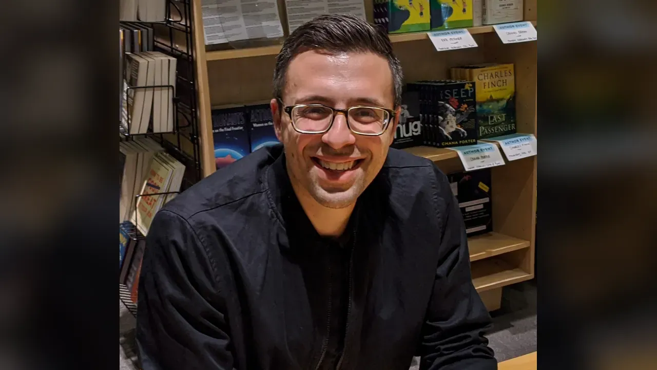 Ezra Klein in a light gray blazer over a dark shirt, photographed on 12 February 2020 during the book tour for Why We're Polarized. The lead image is a 1280 by 720 WebP that fits the upper part of that portrait into a 16:9 frame. Photo by Irn, CC BY-SA 4.0, via Wikimedia Commons.