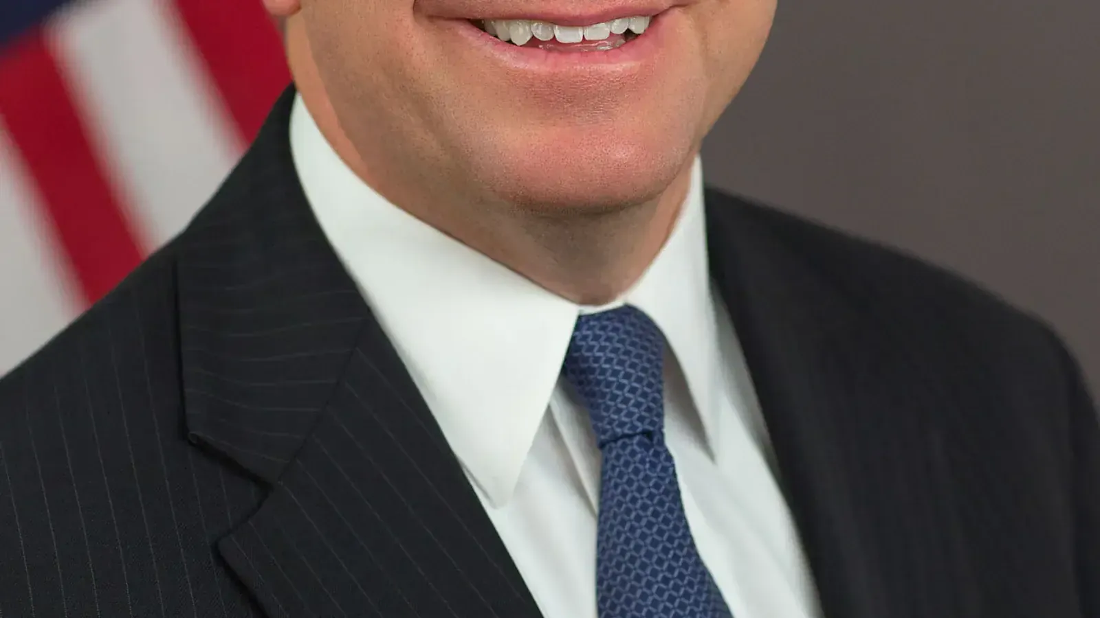 Official portrait of Walter Jay Clayton as chairman of the U.S. Securities and Exchange Commission, in a dark suit and pale blue tie, with the SEC flag behind him, photographed 9 May 2017. Public-domain work of the Commission, via Wikimedia Commons.
