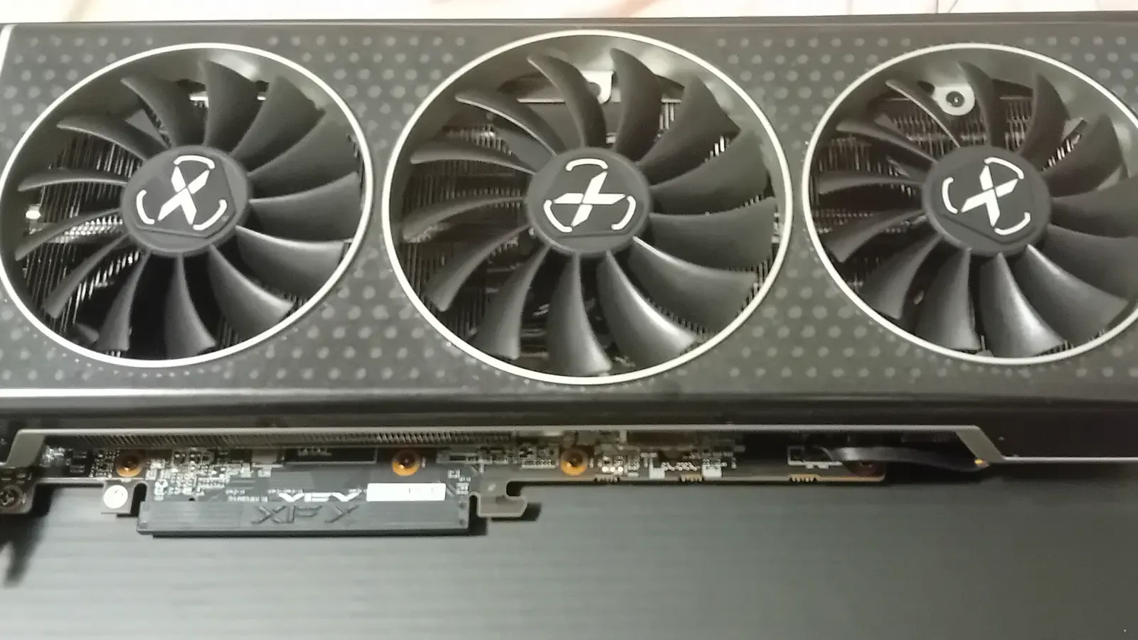 A hand holds an XFX Radeon RX 6750 XT graphics card above a desk, photographed 2 December 2024. Photo by VladoKosto, CC BY 4.0, via Wikimedia Commons.